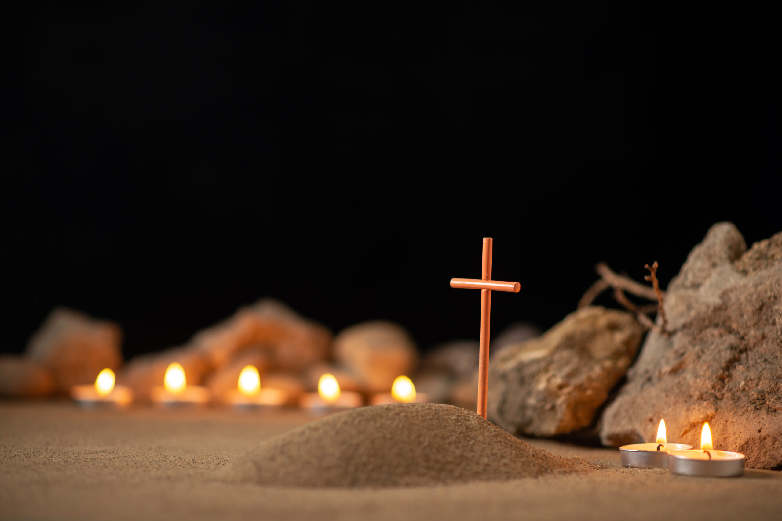 cross and candles in front of a tomb
